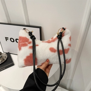 Pink and white cow print plush shoulder bag with black strap and golden ring detail