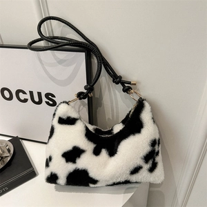 Fuzzy cow print shoulder bag with gold rings and black strap in a minimalist style