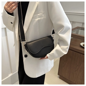 Detail of a black matte PU saddle bag with a contrast wide strap and gold hardware