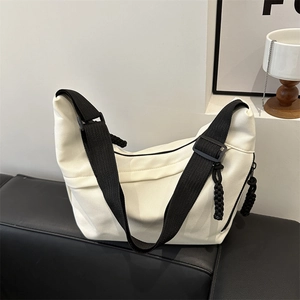 Minimalist white canvas tote bag with contrast black shoulder strap and woven zipper pull