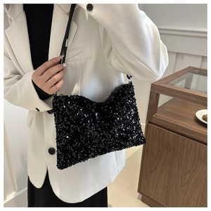 Close-up of black sequined shoulder bag on model wearing white blazer for elegant style