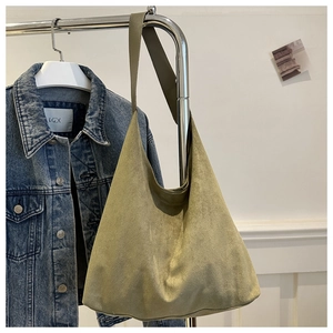 Detail of olive green suede hobo bag hanging with a denim jacket for daily commute