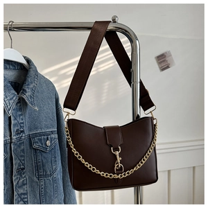 Detailed view of dark brown faux leather bag with gold metal chain and broad strap