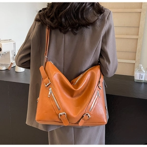 Detail of caramel orange hobo bag with vintage metal zippers and soft PU leather texture
