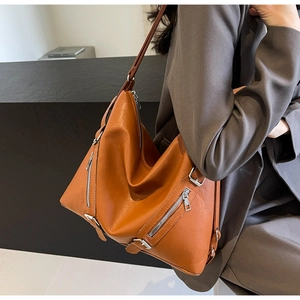 Detailed side view of orange leather tote bag with silver zippers and adjustable strap