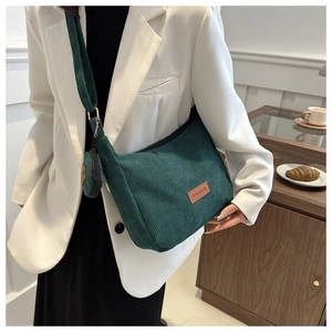 Detail of dark green corduroy tote bag with round coin purse and brown leather tag