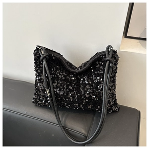 Detail of black sequin shoulder bag showing reflective texture and knotted strap design