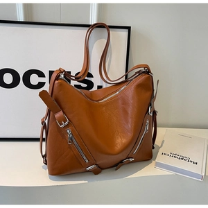 Close-up of caramel leather shoulder bag with decorative silver zippers and adjustable strap