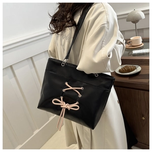 Vue détaillée du sac cabas noir brillant avec laçage décoratif en ruban rose