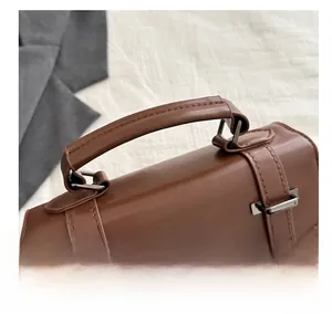 Dettaglio dell'ampio manico in pelle PU marrone e fibbia in metallo vintage per borsa