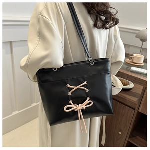 Détail du sac cabas noir avec lacets roses, nœud et accents d'oeillets métalliques