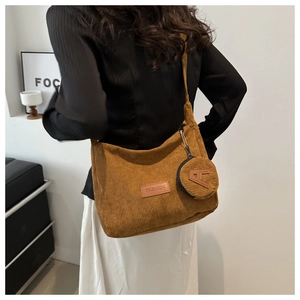 Rear view of a model wearing a brown corduroy crossbody hobo bag with a mini coin pouch