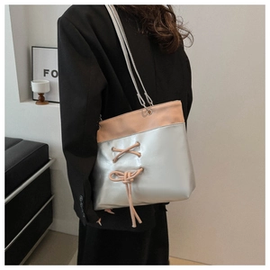 Sac fourre-tout argenté chic avec détails à lacets beiges porté par un mannequin