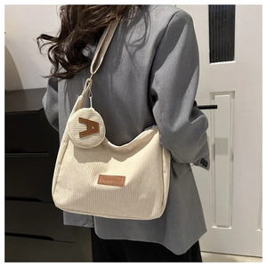 Close-up of off-white corduroy tote bag with mini round pouch and leather fashion label