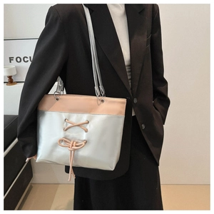 Détail du cabas argent et rose avec nœud lacé porté sur l'épaule d'un modèle