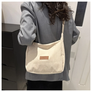 Detail of cream corduroy crossbody bag featuring a brown leather 'FASHION' label patch