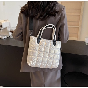 Gros plan d'un sac cabas matelassé blanc avec des sangles noires dans un café