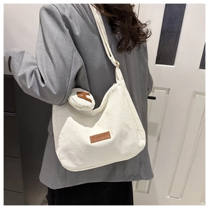 Detail of white corduroy crescent crossbody bag with mini pouch and leather fashion label