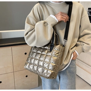 Sac fourre-tout matelassé doré avec bandoulière noire dans un décor intérieur minimaliste