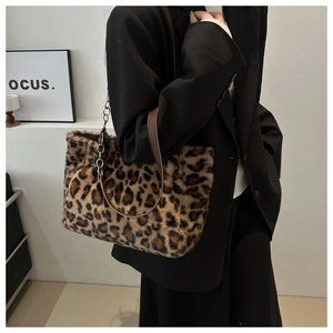 Detail of leopard print plush tote bag with brown leather strap and silver metal chain