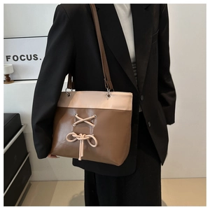 Détail d'un sac cabas bicolore avec un nœud chic et une sangle en cuir synthétique