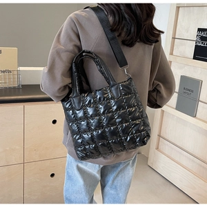 Detail of black quilted puffer tote bag with glossy finish and wide adjustable strap