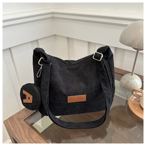 Detail of black corduroy tote with a round coin pouch and brown leather fashion label