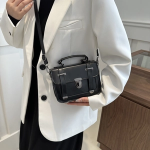 Dettaglio di una borsa a tracolla vintage in pelle nera con hardware argento su abito