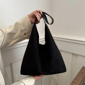 Minimalist black suede tote bag with leather shoulder straps shown in an indoor setting