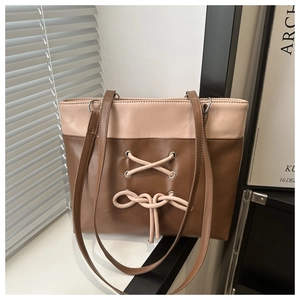 Détail du sac cabas en cuir rose et marron avec nœud et œillets métalliques