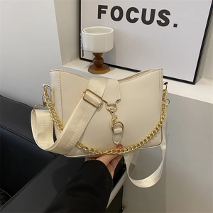 Retro cream crossbody bag with gold chain and adjustable wide woven strap in minimal setting