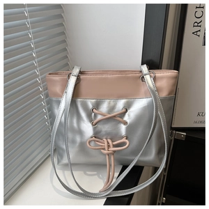 Sac cabas argenté avec lanières roses et détail de nœud sur fond de volet blanc moderne