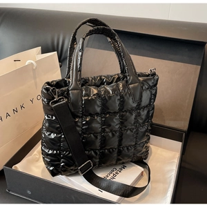 Gros plan d'un sac cabas noir en nylon matelassé dans un coffret avec bandoulière