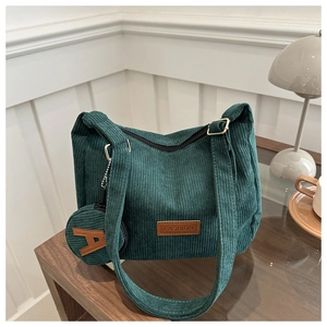 Detail of dark green corduroy tote bag with small round coin purse and brown leather label