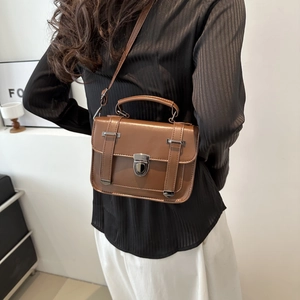 Dettaglio della borsa a tracolla marrone vintage con chiusura a rotazione argento e pelle PU