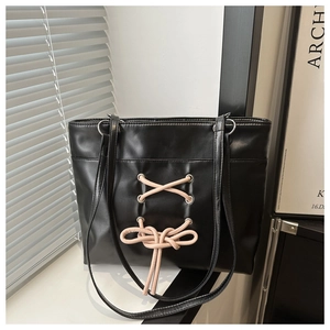 Détail du cabas noir en similicuir avec laçage en ruban rose et nœud décoratif