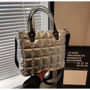 Détail d'un sac cabas matelassé argenté avec finition métallisée et anses noires