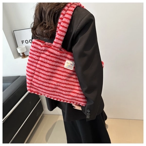 Détail du sac cabas en laine d'agneau rayée avec étiquette tissée de marque sur le côté