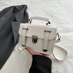 Dettaglio di una borsa a mano bianca quadrata con fibbia in metallo scuro e manico solido