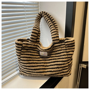 Detailaufnahme der gestreiften Lammwoll-Tasche mit weicher Textur und Markenetikett