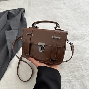 Dettaglio borsa vintage marrone con chiusura a pressione canna di fucile e manico