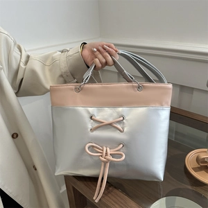 Sac cabas rose et argenté avec nœud, porté par une femme en manteau beige