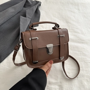 Dettaglio ravvicinato della borsa vintage marrone scuro con fibbia in metallo e tracolla