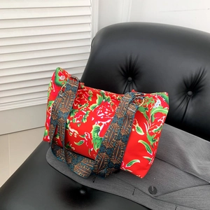 Sac fourre-tout à fleurs rouges avec bandoulière ethnique sur un canapé en cuir