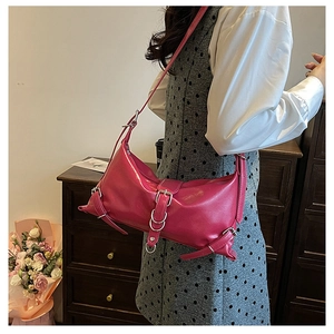 Detail of rose pink glossy shoulder bag with silver buckles and metal hardware accents