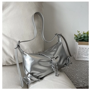 Close-up of silver metallic shoulder bag with belt buckles and edgy Y2K design