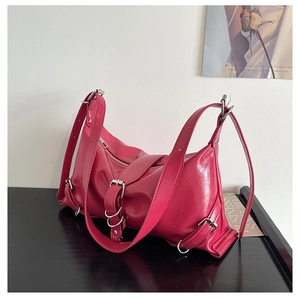 Close-up of fuchsia motorcycle-style underarm bag with silver buckles and wrinkled texture