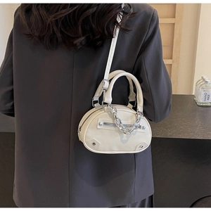 Close-up of mini off-white crossbody bag with chunky silver chain and front zip pocket