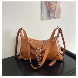 Detail of caramel brown glossy shoulder bag with silver metal buckles and zipper closure