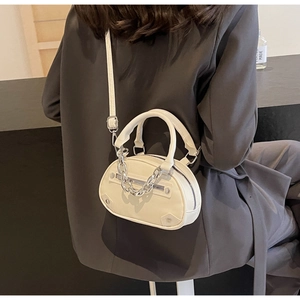 Close-up of a white mini crescent bag with chunky silver chains and dual zip detail